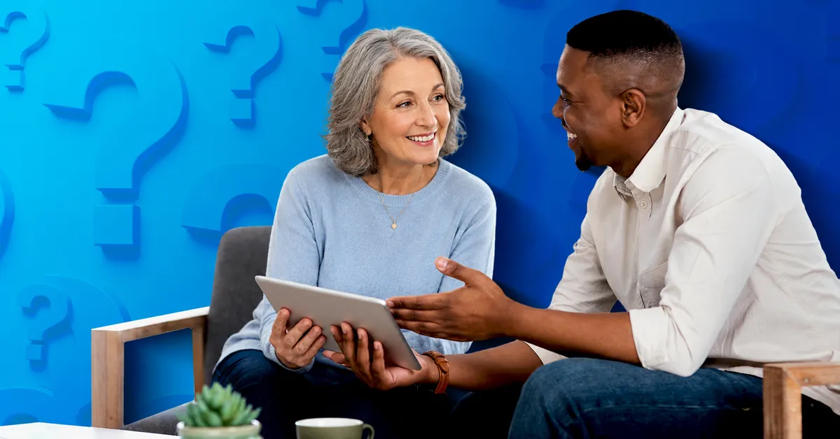 Senior woman and young man discussing and smiling while holding a digital tablet against a blue question mark background