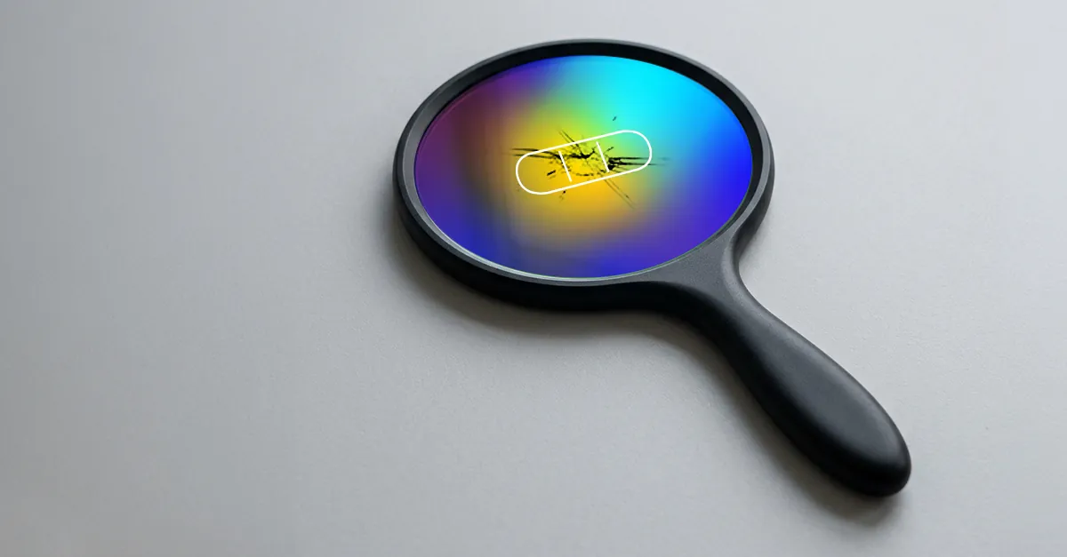 Colorful magnifying glass with scratches on a white surface, highlighting cracked glass detail.