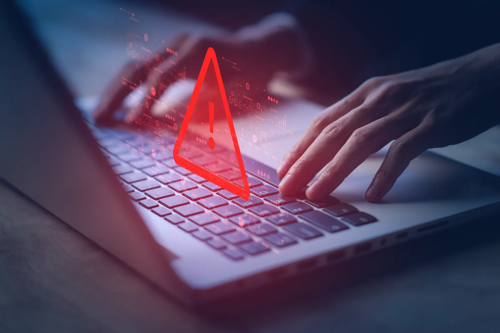 Hands typing on a laptop keyboard with a red warning alert symbol hovering above keys indicating a security or error issue.