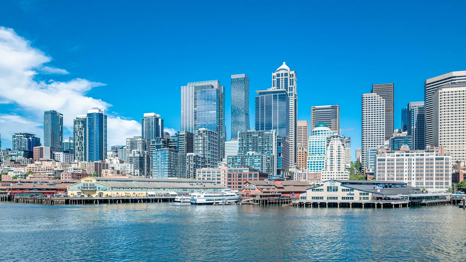 Seattle city skyline with tall skyscrapers and waterfront under a clear blue sky.