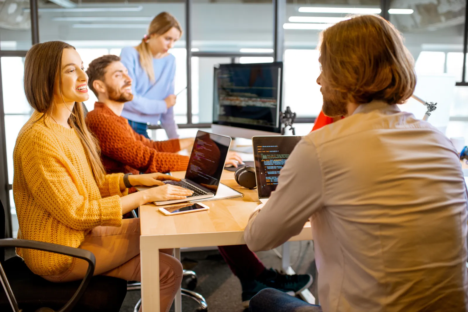 a group of people sitting at a table with laptops