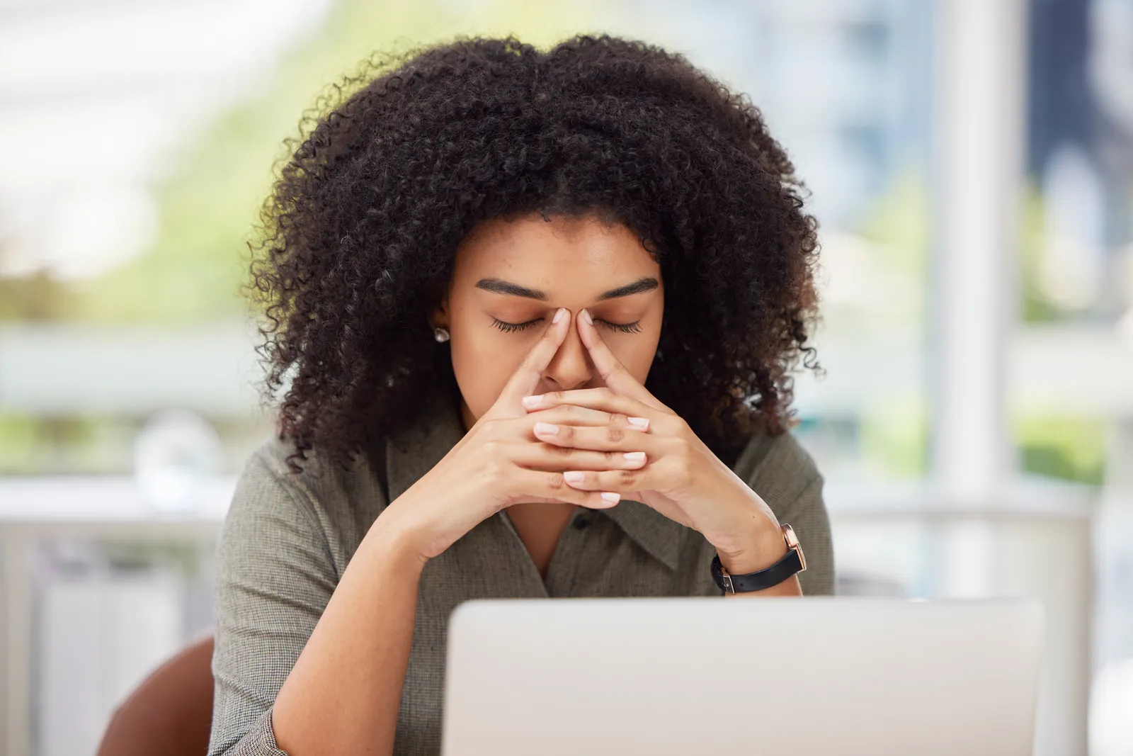 national-city-managed-it-services-photo Stressed woman rubbing her eyes while working on a laptop in a bright modern office environment.