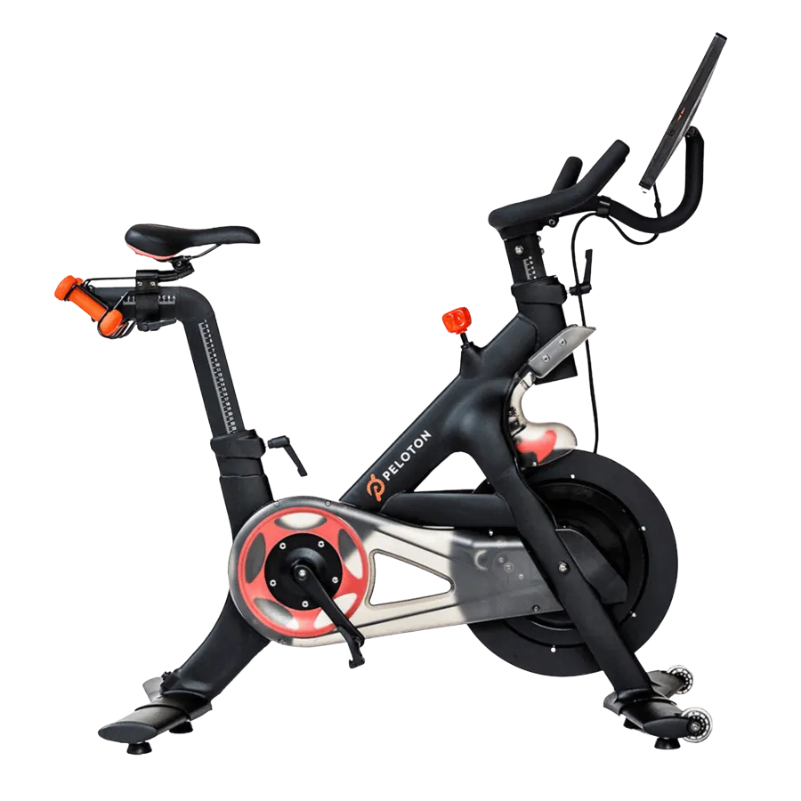 Black and red Peloton stationary exercise bike with screen and adjustable seat isolated on black background